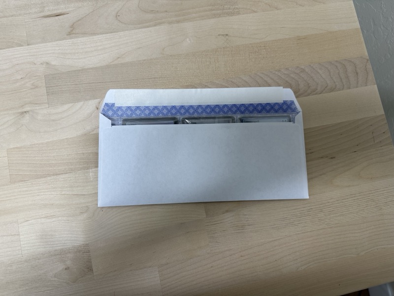 Cards in binder sleeve inserted into a plain white envelope, showing a snug fit